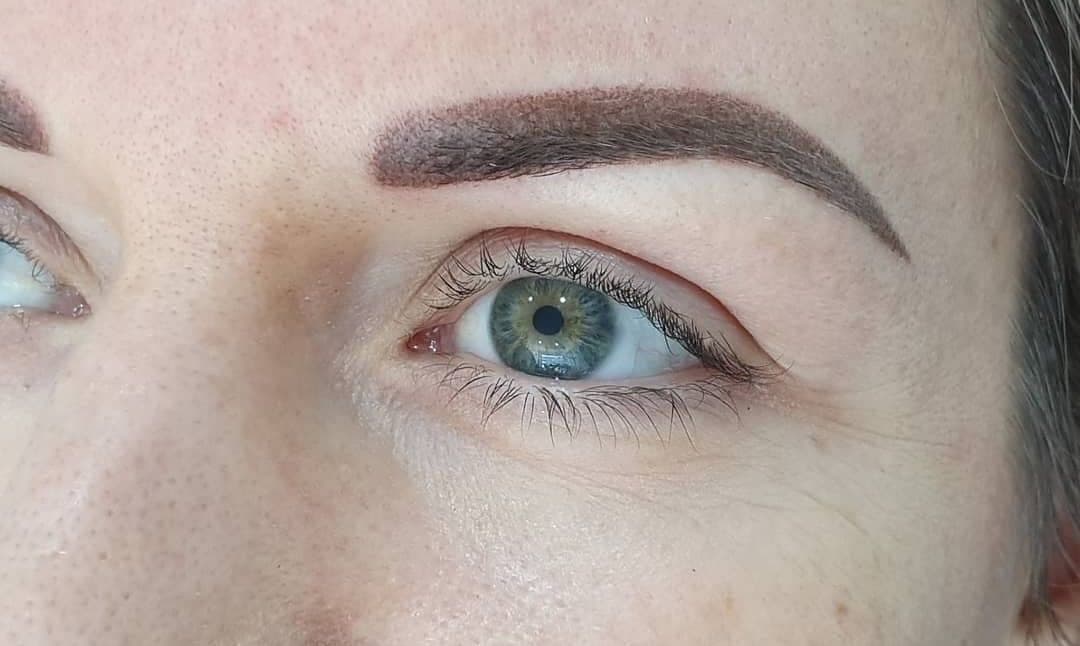 Shaded powder brow framing a blue-green eye