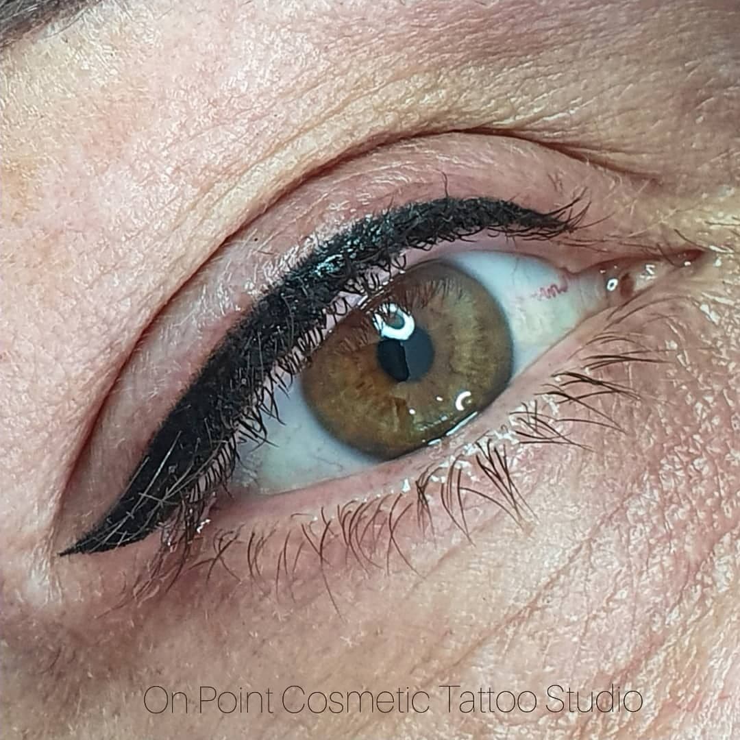 Designer eyeliner tattoo with a crisp wing on a brown eye