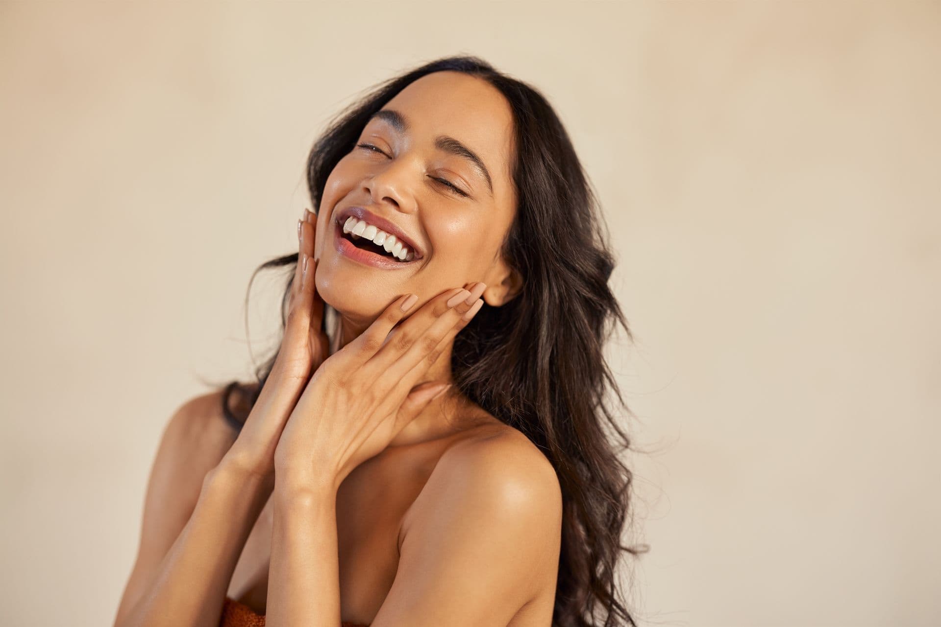 A smiling woman with her hands to her face