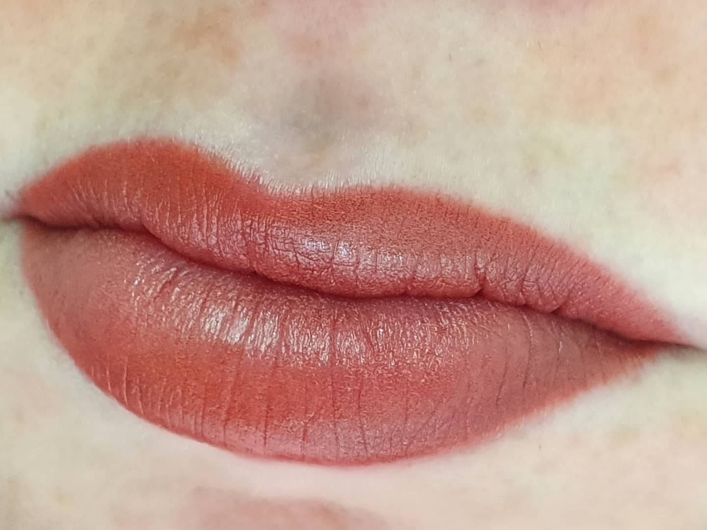 Full lip tattoo in a warm coral tone
